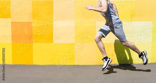 Unrecognizable man running against bright wall photo