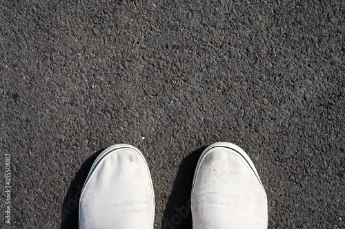 Two white sneakers on black asphalt. Top View. Copy space.