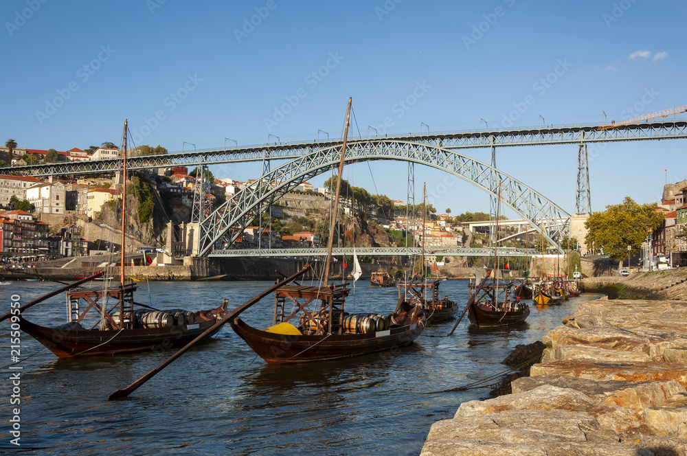 View of the Douro River with rabelo boats, the iconic Dom Luis Bridge and the Ribeira neighbourhood in Porto, Portugal; Concept for travel in Portugal and visit Porto