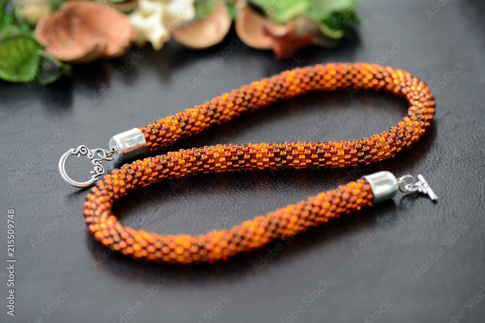 Bead crochet necklace amber color on a dark background close up