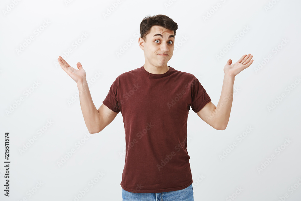 Who knew it happen. Portrait of clueless unaware attractive man in red t-shirt, raising palms high and shrugging, lifting eyebrow in no idea expression, being quesitoned and indifferent to situation Who knew it happen. Portrait of clueless unaware attractive man in red t-shirt, raising palms high and shrugging, lifting eyebrow in no idea expression, being quesitoned and indifferent to situation
