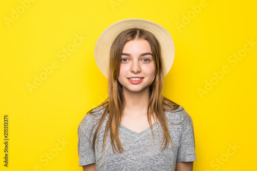 Beautiful beauty young woman in gray shirt and straw hat on yellow background.