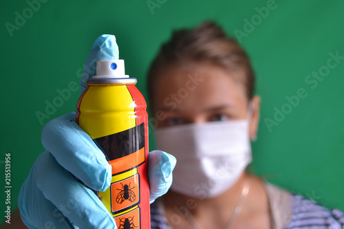 Aerosol for insect control in the hands of a woman wearing a mask. photo