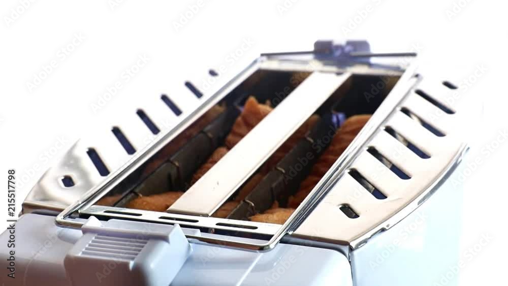 A view of pastries in process a toasting device at kitchen. Fried toast slices jump from the toaster.
