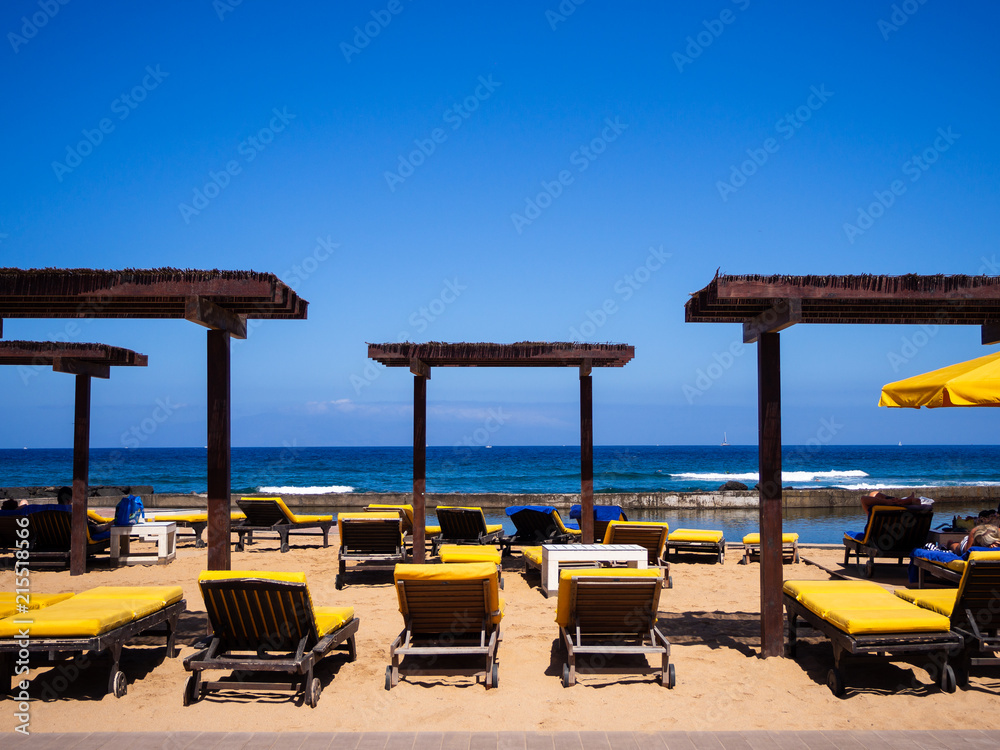 Empty sun beds on a beach at Playa de Las Americas, Tenerife, Spain