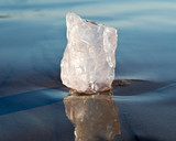 Gem grade rough Rose Quartz chunk from Madagascar lying on wet sand  in front of the lake at sunrise.