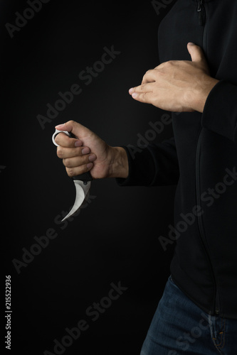 Crime and violence concept, a murderer with a karambit knife trying to kill victim