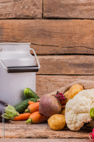 Different vegetables and enamelware milk churn. Still life. Wooden desk table background. photo