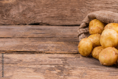 Young potatoes in a bag. Wooden desk table background. photo