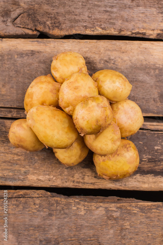 Pile of potatoes top view. Wooden desk background. photo