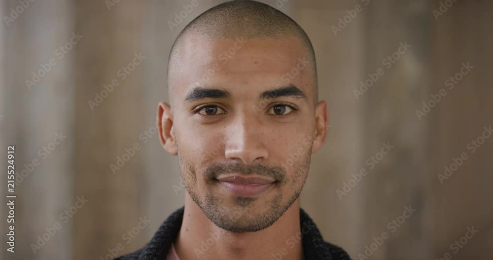 close up portrait of attractive young mixed race man smiling enjoying happy lifestyle looking at camera wooden background slow motion