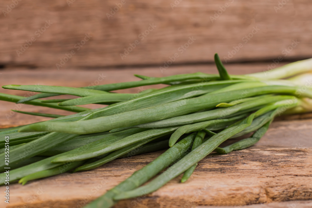 Green onion on the table close up. Wooden desk background. Green onion on the table close up. Wooden desk background.