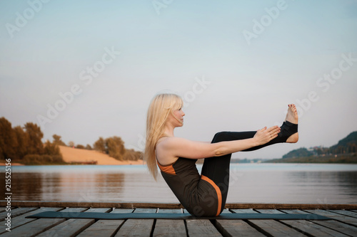 a woman practicing yoga. healthy lifestyle. yoga on the river bridge