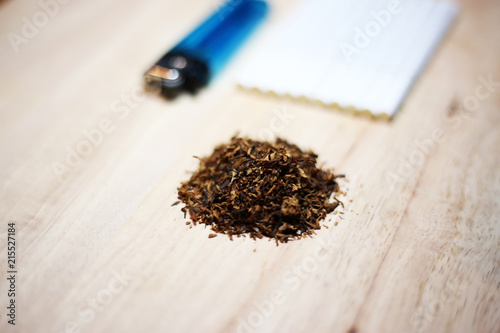 Closeup dry tobacco leaves with cigarette and lighter isolated in wood plate.