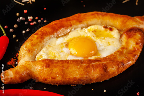 Traditional Georgian and Armenian cuisine. Khachapuri with suluguni cheese and egg yolk on a black background. background image. Copy space, selective focus photo