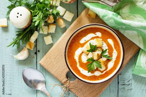 Fényképezés Puree soup tomato with croutons and cream in a bowl on a kitchen wooden table