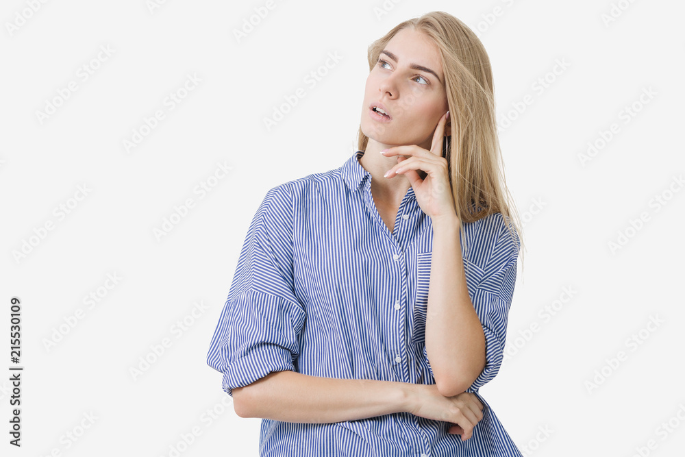 Portrait of young blonde european girl wearing blue striped shirt thinking about something over white background Portrait of young blonde european girl wearing blue striped shirt thinking about something over white background