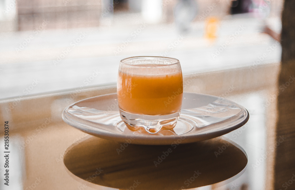 Healthy shot of functional organic fruit, vegetable and spice in a small glass on a white saucer in the bright window of a health bar Healthy shot of functional organic fruit, vegetable and spice in a small glass on a white saucer in the bright window of a health bar