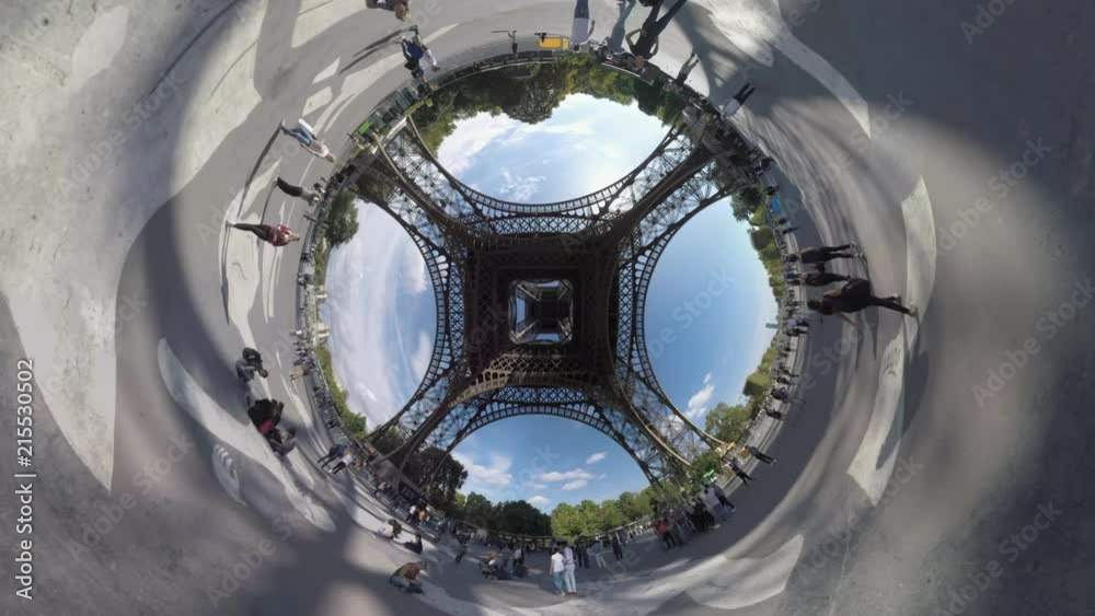 PARIS, FRANCE - SEPTEMBER 29, 2017: Spherical timelapse shot of people walking near the Eiffel Tower, bottom view of city landmark against blue sky