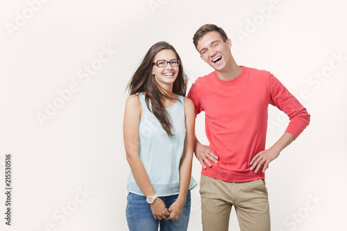 Happy young lovely couple standing together and laughing. Studio shot over white background. Friendship, love and relationships concept