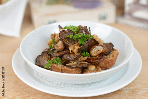 Golden fried mushrooms with onions and greens on a white plate