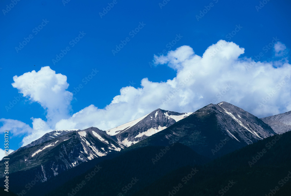 Beautiful alpine ice mountains peaks with snow, summer time, blue sky background.