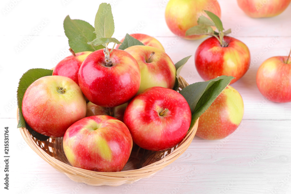 A lot of fresh ripe apples in a basket on a white wooden background A lot of fresh ripe apples in a basket on a white wooden background