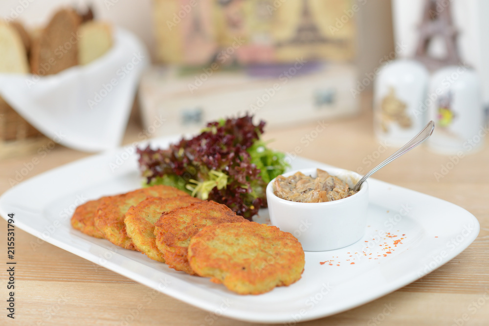 Traditional Belarus potato pancakes (draniki) with sauce cream in a plate at a cafe Traditional Belarus potato pancakes (draniki) with sauce cream in a plate at a cafe