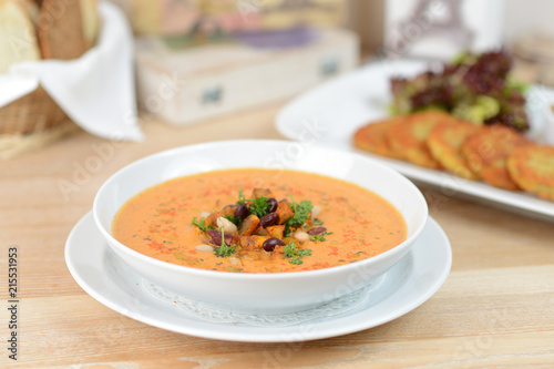 pumpkin soup with beans and croutons on a white plate