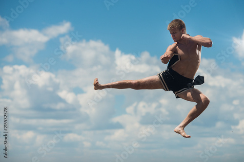 Man flying kick in sky background