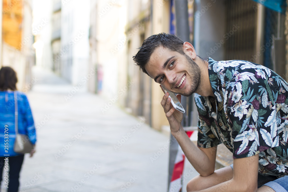 portrait of smiling young man with mobile phone on the street
