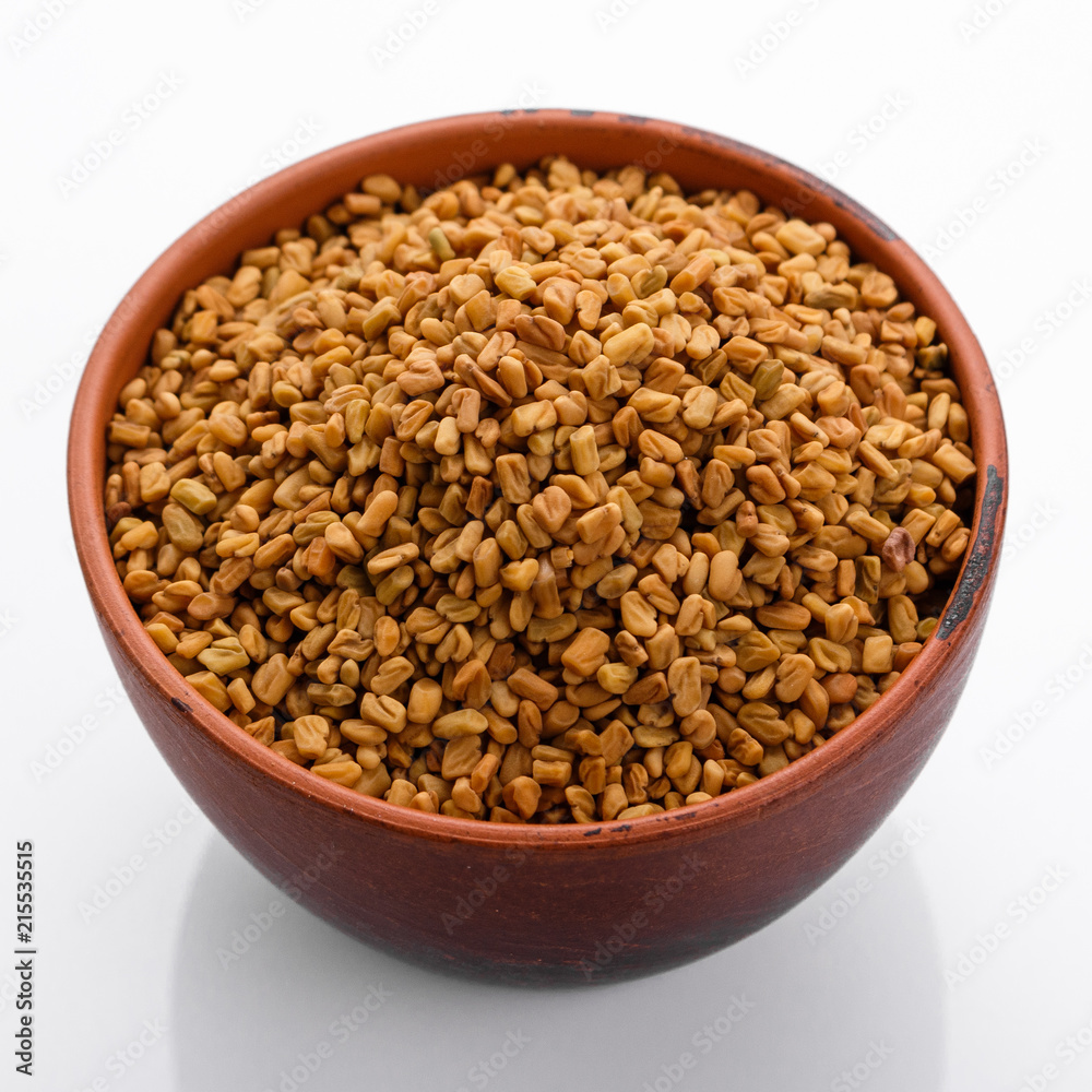 fragrant grains of fenugreek on a white background fragrant grains of fenugreek on a white background