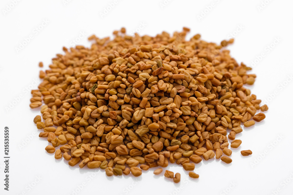 fragrant grains of fenugreek on a white background fragrant grains of fenugreek on a white background