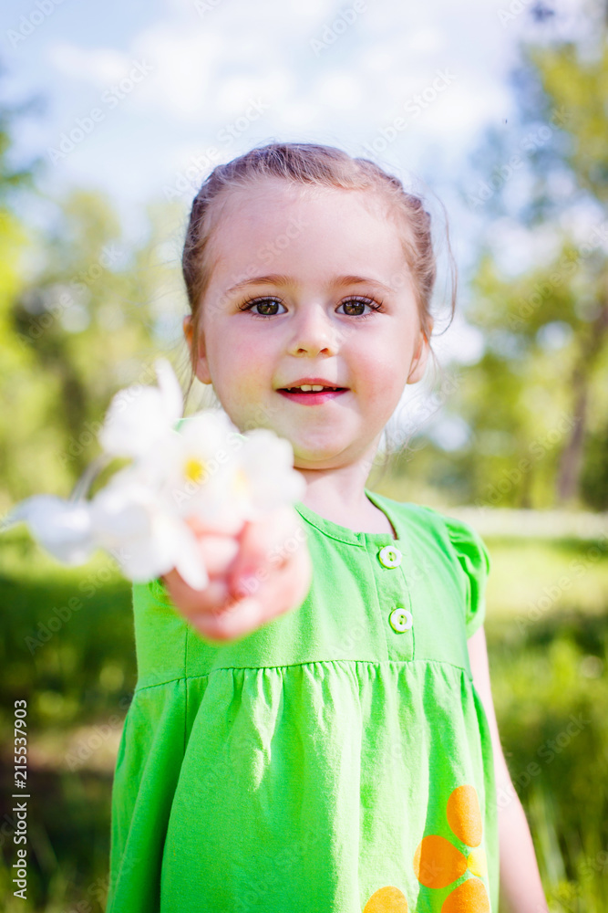 little girl in a green dress in a clearing in the summer with flowers little girl in a green dress in a clearing in the summer with flowers