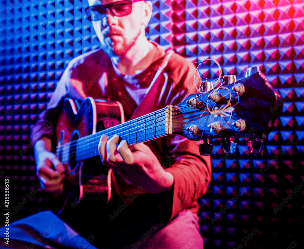 Obraz premium Young man playing on the acoustic guitar in sound recording studio.