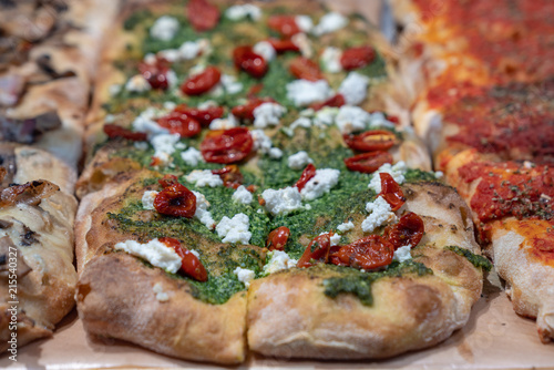 Crusty pizza slices with dried tomatos, pesto and fresh cheese