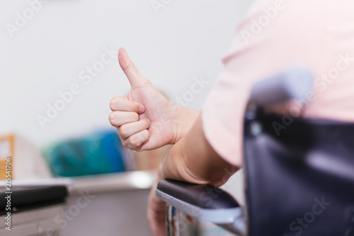 Close up of male patient on wheelchair giving thumbs up as a sign of happy support.