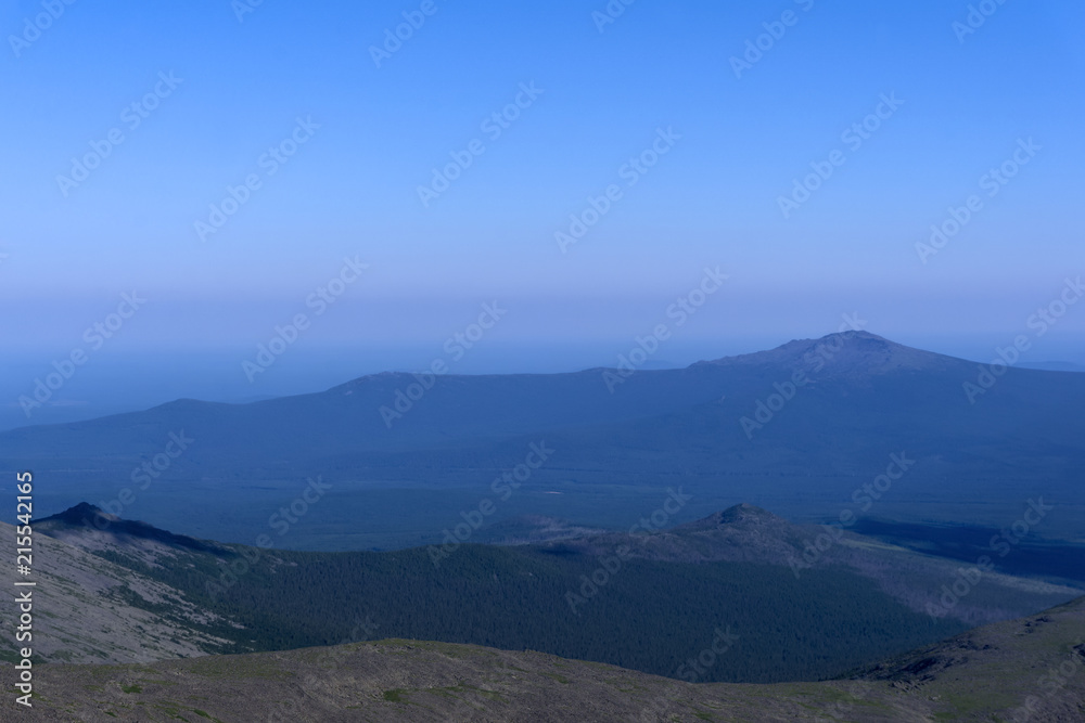 gently sloping mountains of the Northern Urals in a blue atmospheric haze..