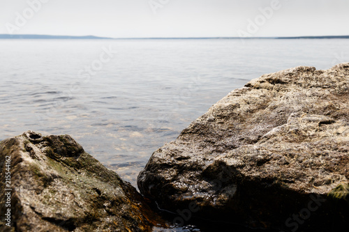 Big stones lie on sea beach. Coast. Nature background. Water with waves. Seascape