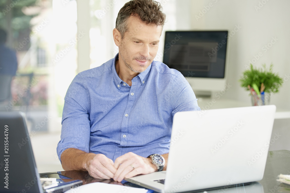 Middle aged businessman working on notebooks at the office Middle aged businessman working on notebooks at the office