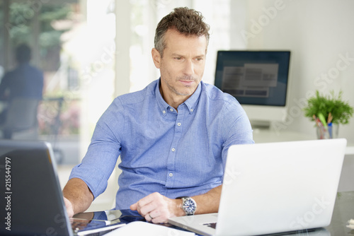 Middle aged businessman working on notebooks at the office