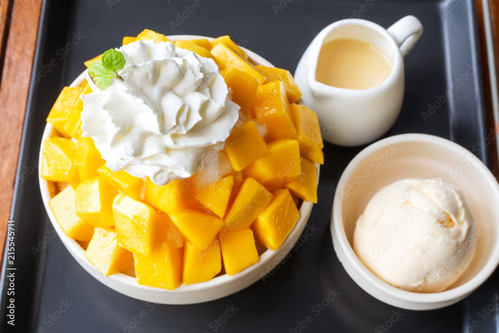 Shaved ice dessert served with mango sliced and whipping cream. Sweet dessert in Korean style. Local name, Bingsu. Shaved ice dessert served with mango sliced and whipping cream. Sweet dessert in Korean style. Local name, Bingsu.