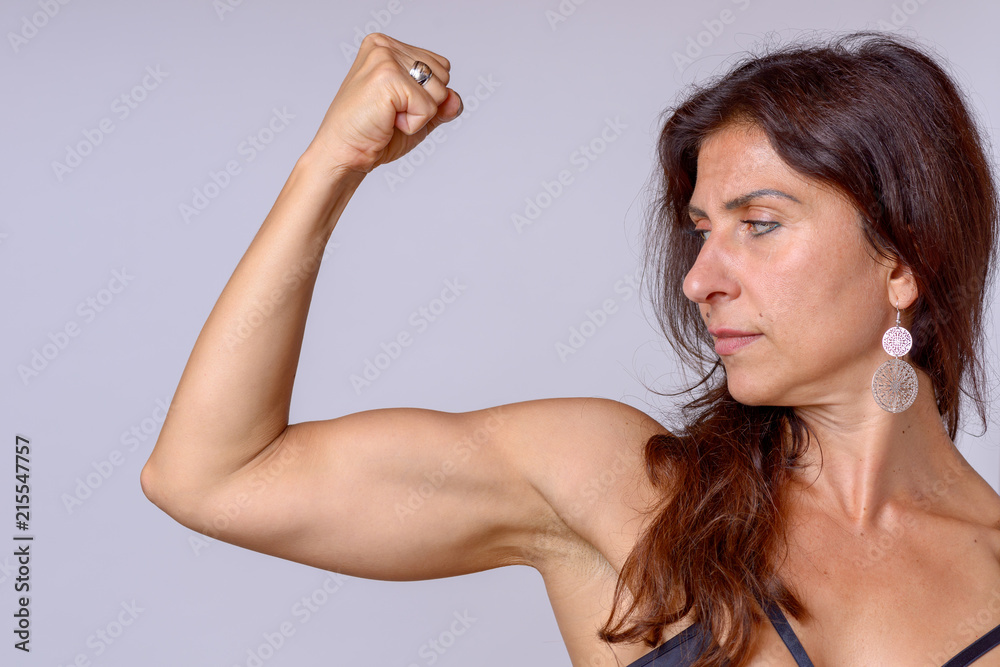Strong fit mature woman flexing her arm muscles Stock Photo