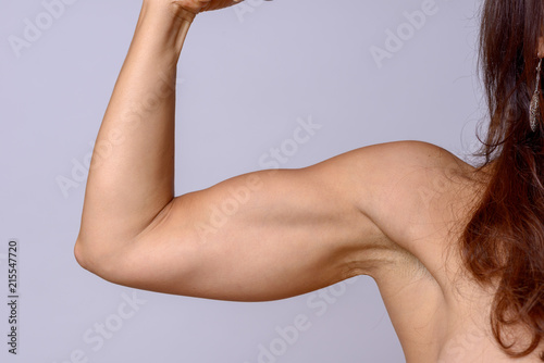 Strong fit mature woman flexing her arm muscles