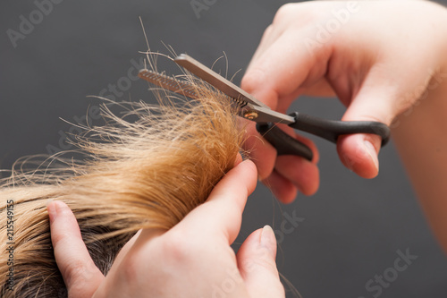 Trimming blond hair with scissor