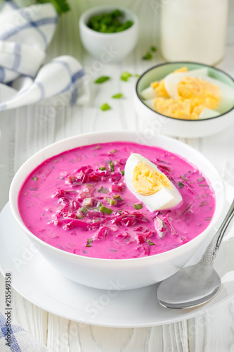 Cold borsch, summer beet soup with fresh cucumber, radish and boiled egg in white bowl. Traditional European food, delicious lunch