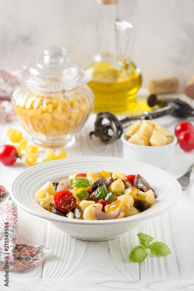 Italian pasta with fried vegetables and mushrooms, zucchini, cherry tomatoes, champignon, cheese and Basil. White plate Italian pasta with fried vegetables and mushrooms, zucchini, cherry tomatoes, champignon, cheese and Basil. White plate