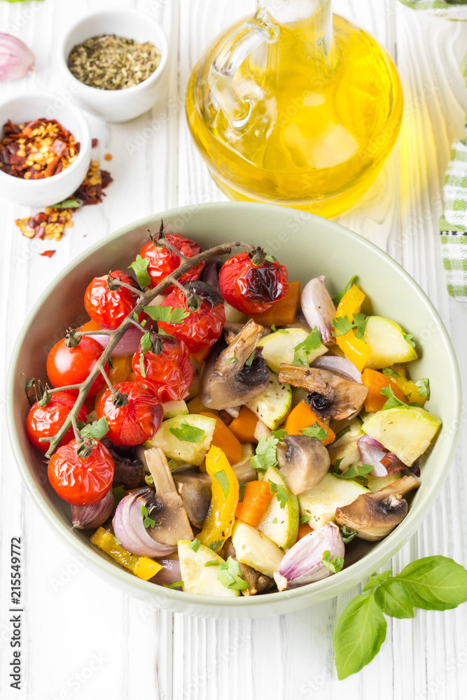 Baked vegetables with mushrooms in a bowl. Zucchini, cherry tomatoes on a branch, red onions, bell peppers and garlic. Delicious garnish, vegetarian food, healthy diet Baked vegetables with mushrooms in a bowl. Zucchini, cherry tomatoes on a branch, red onions, bell peppers and garlic. Delicious garnish, vegetarian food, healthy diet