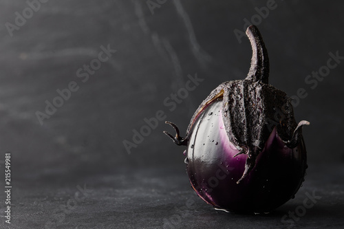 Fresh Italian type eggplant or aubergine with water drops closeup on black background