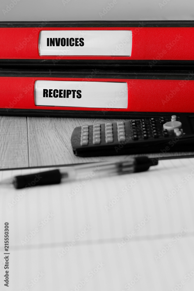 Red folders with invoices and receipts written on the label on a desk with selective colour